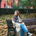 woman in brown coat sitting on brown wooden bench